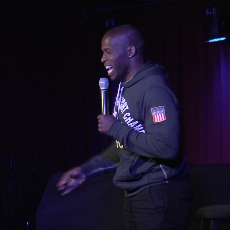 Godfrey on stage at a Cool Beans Comedy show.