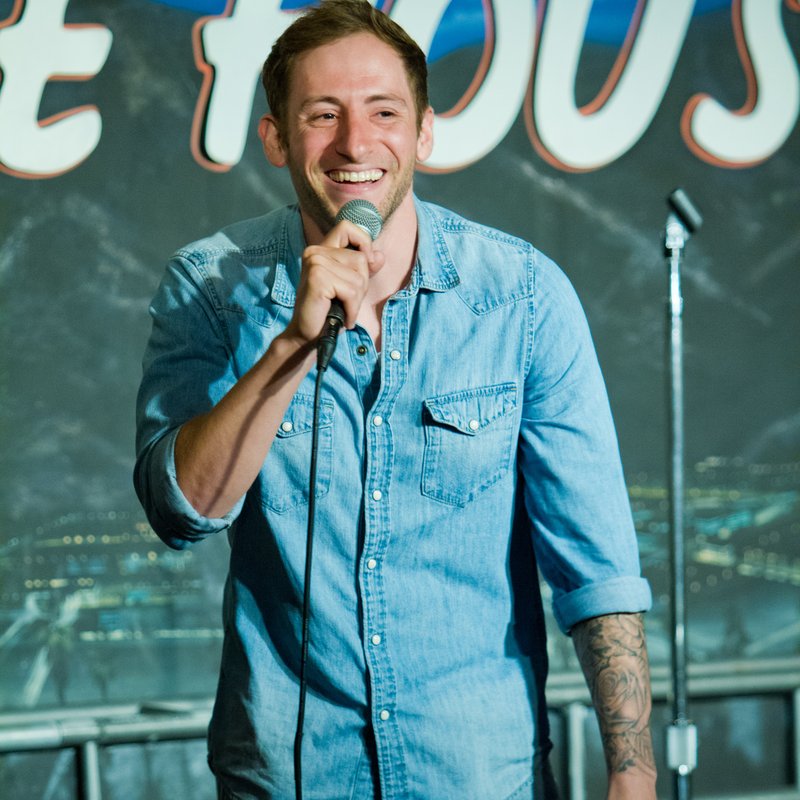 Samuel J Comroe on stage at a Cool Beans Comedy show.
