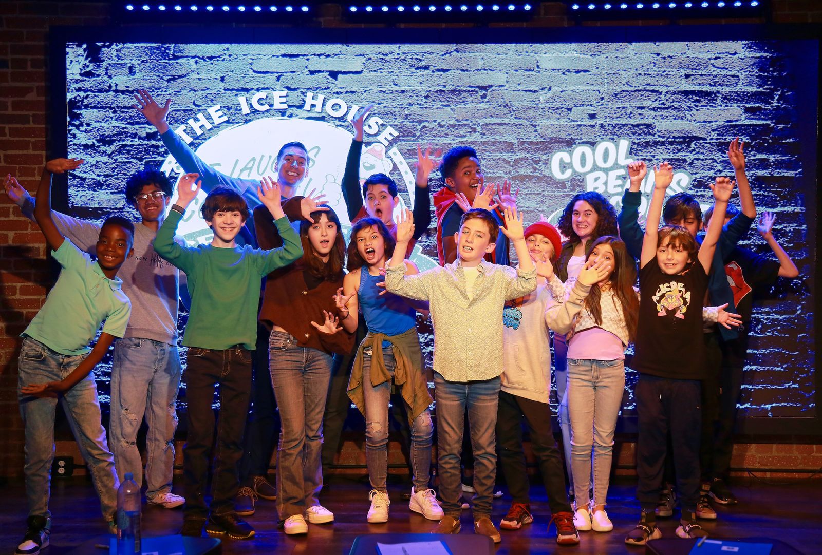A kids class cheering with their arms up on the Ice House stage.
